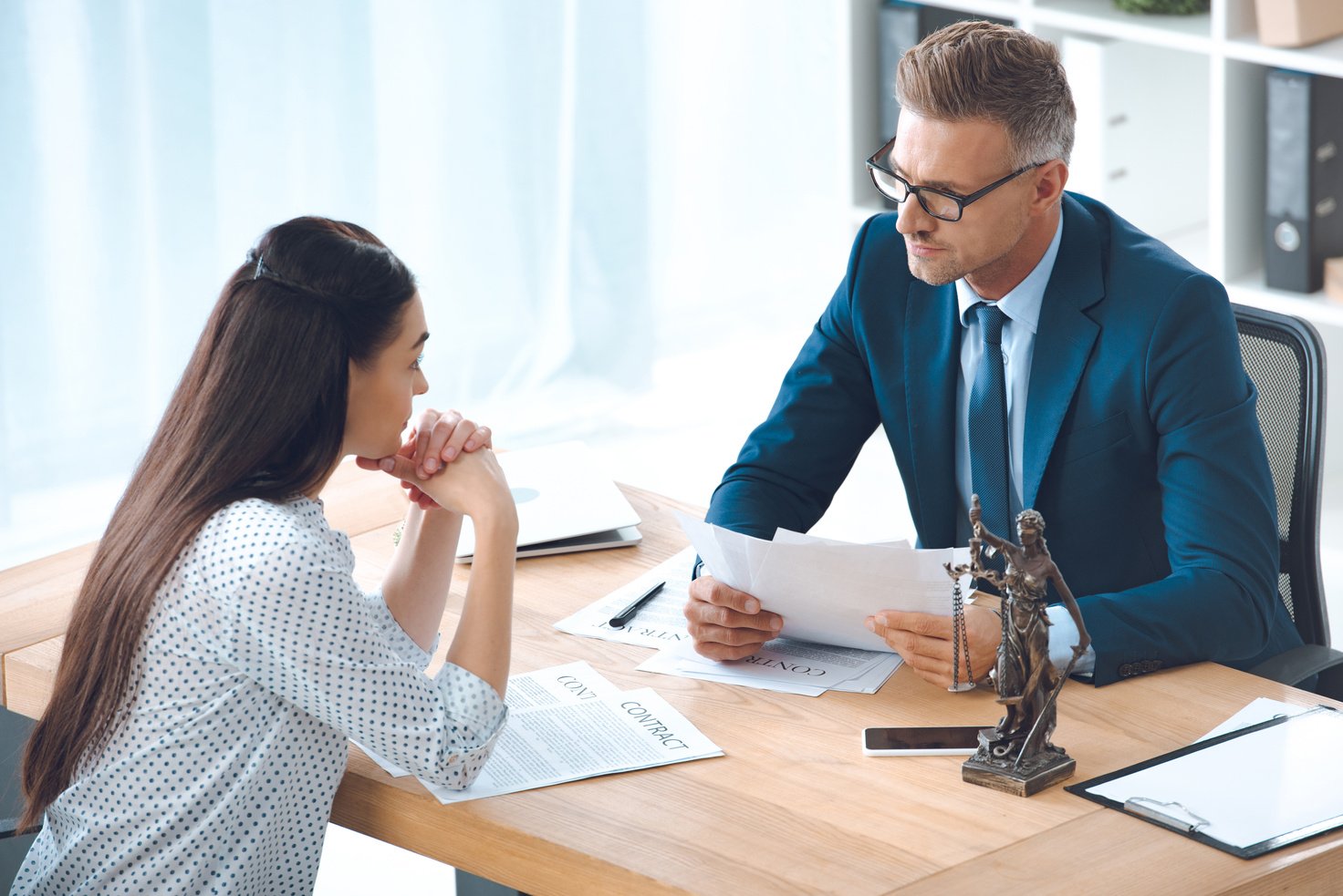 high angle view of lawyer and client looking at each other while discussing contract in office